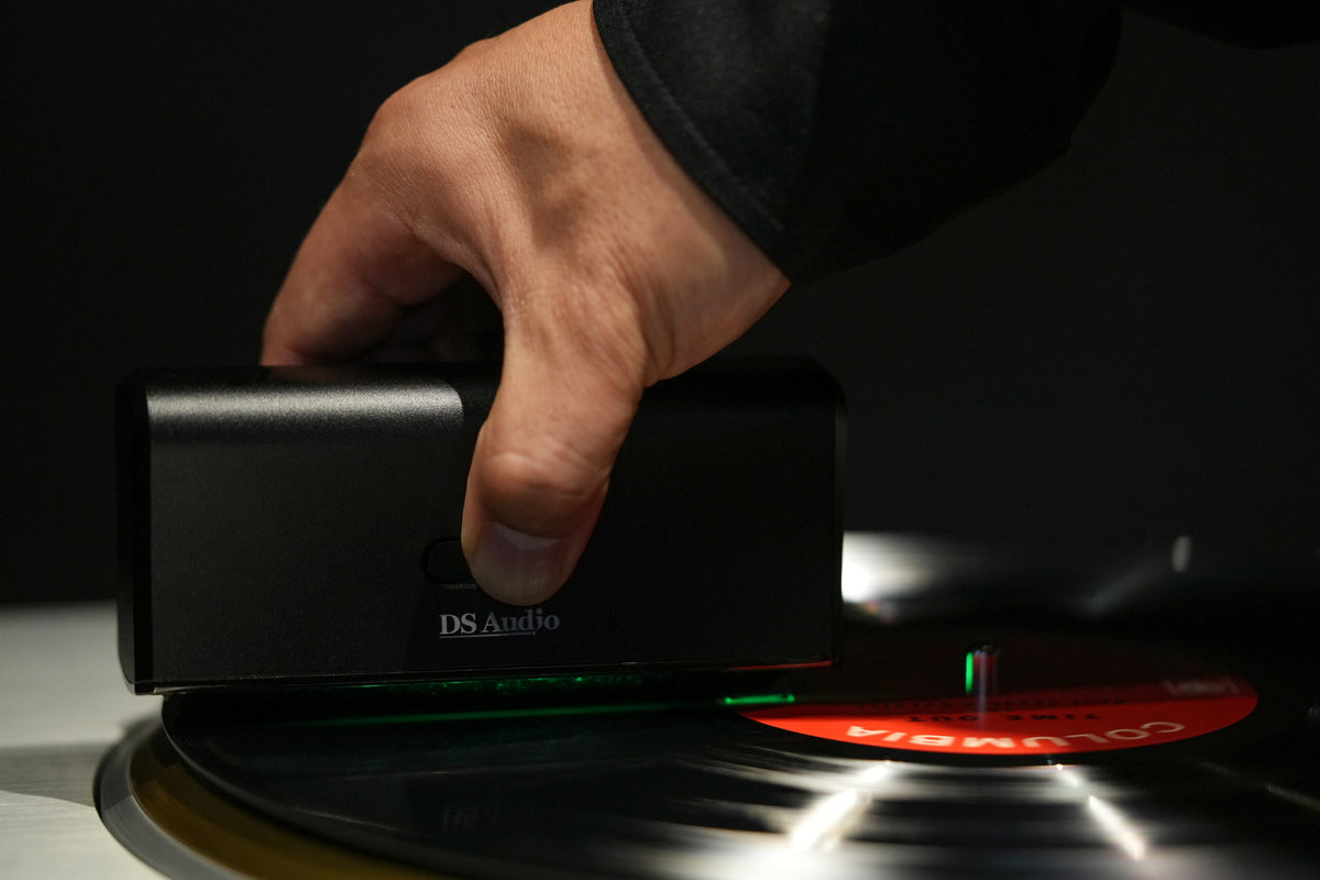 DS Audio SC-001 tenue à la main pendant le nettoyage d’un disque vinyle sur une platine.